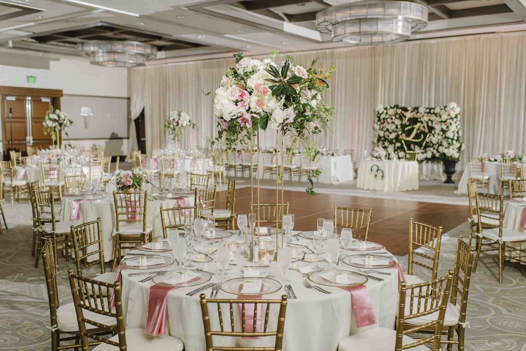 A Chair Affair - reception hall with gold chairs and stunning floral centerpieces