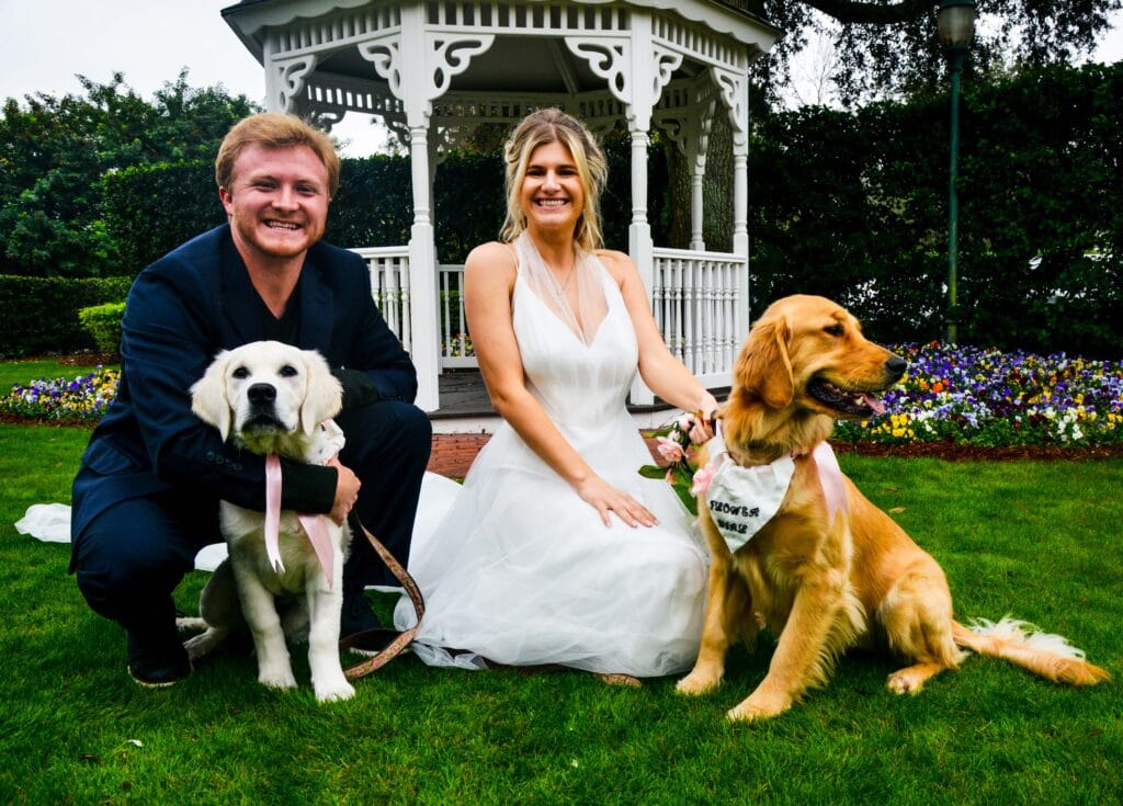 bride and groom kneeling and holding their dogs outside at Celebration Golf Club in front of gazebo