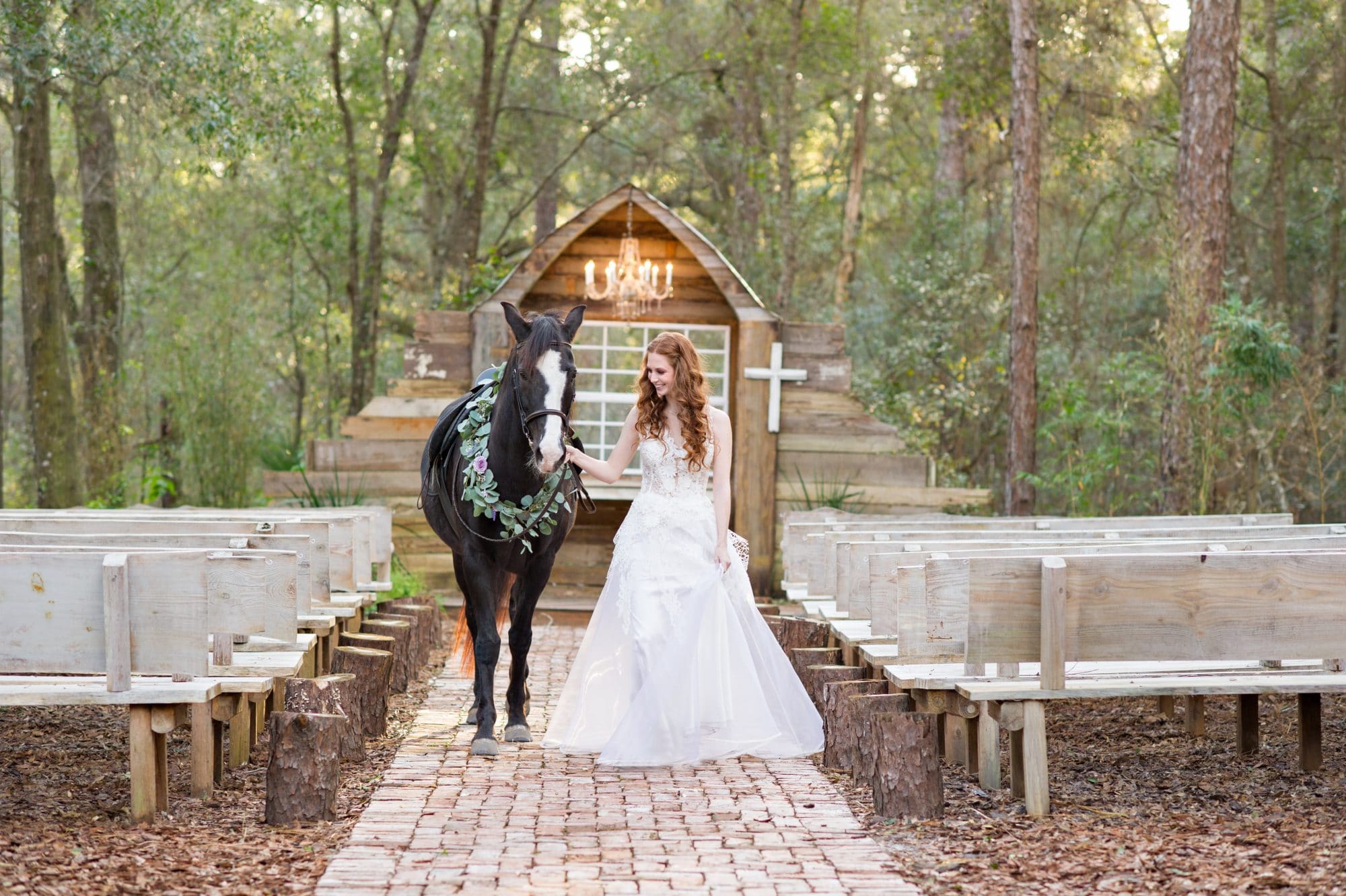 Bridle Oaks Barn - bride leading horse through woodsy outdoor ceremony space