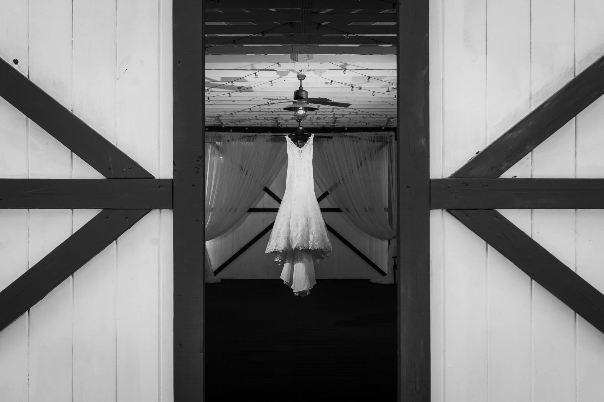 Bridlewood-Ranch-Wedding dress hanging in barn between barn doors