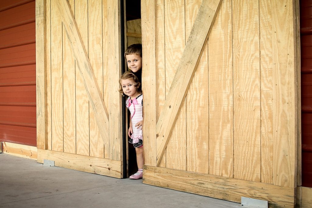 children peeking out from behind closed barn door at the Diamond L Venue in Volusia County, near Deltona, FL