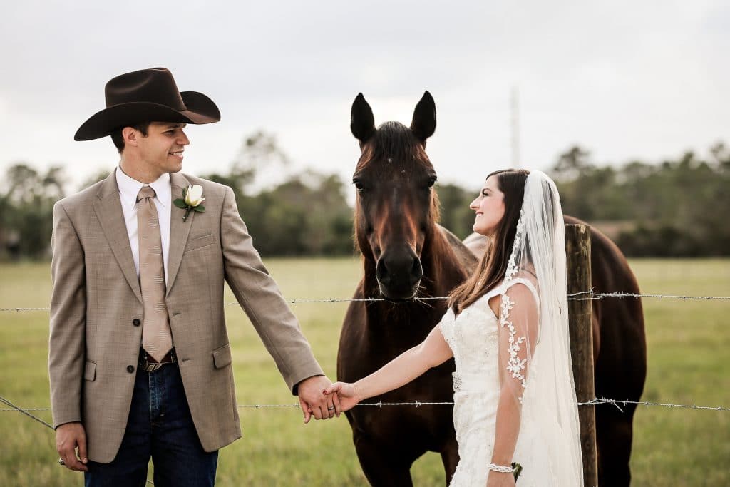 bride and groom posing next to horse at the Diamond L Venue in Volusia County, near Deltona, FL