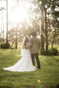 country bride and groom in cowboy hat at the golden hour in a field at the Diamond L Venue in Volusia County, near Deltona, FL