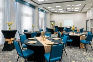 Banquet set up, teal blue chairs, black tablecloths, orange runners, yellow floral centerpieces, Orlando, FL
