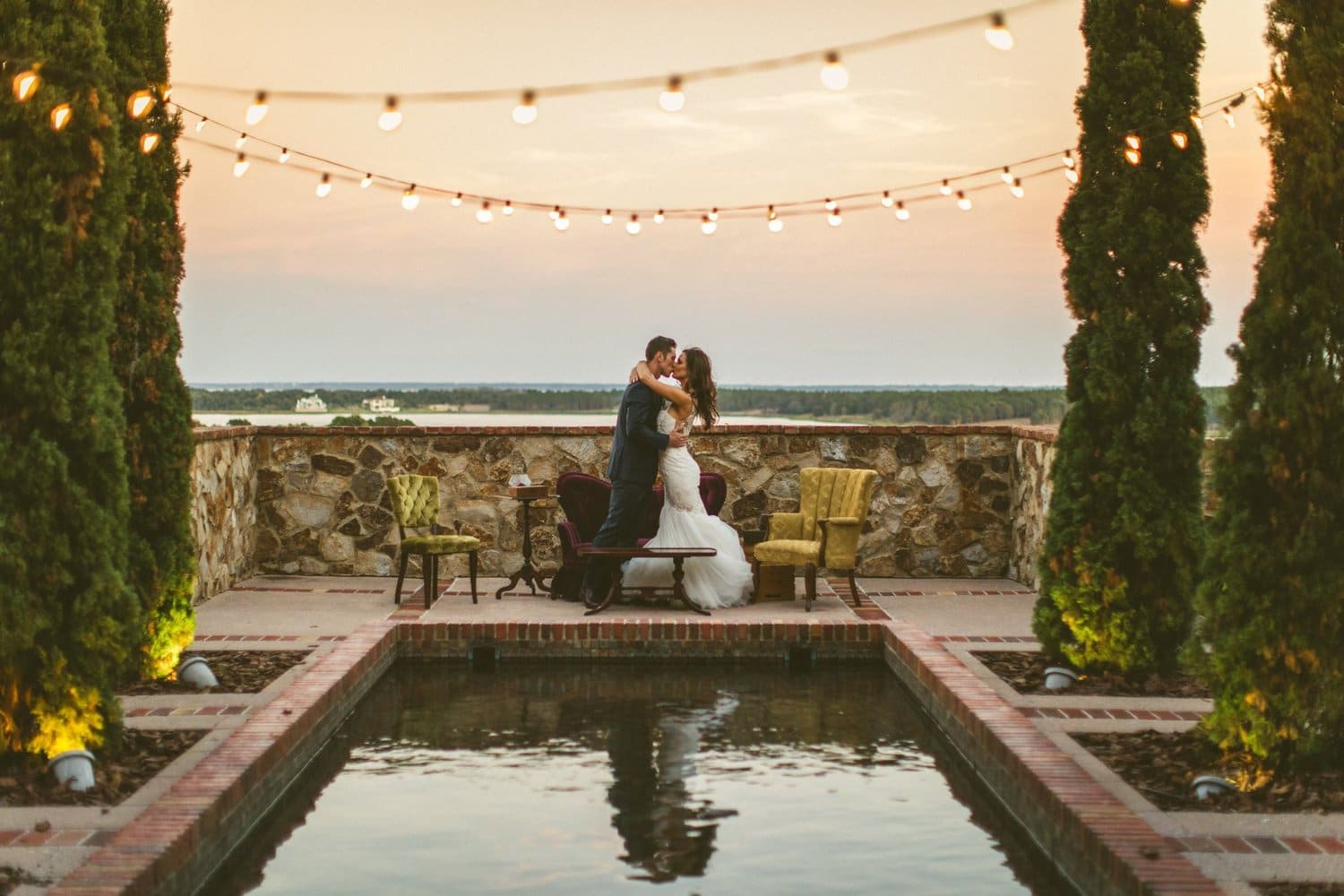 bride and groom kissing reflected in Tuscan inspired viewing pool