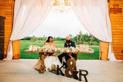 Mystical Winds sweetheart table at wedding reception with view of fields behind them