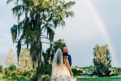 Mystical Winds bride and groom outside underneath a moss covered tree and a rainbow