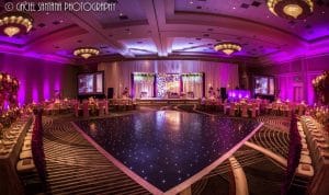 hotel ballroom set up for wedding reception with pink lighting and large dance floor