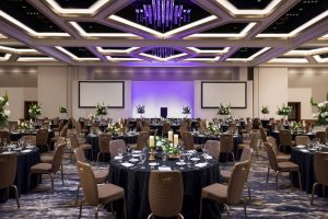 hotel ballroom wedding reception set up with brown chairs, candle and floral centerpieces, and unique grid ceiling