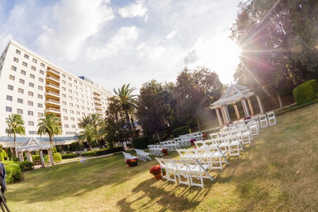 white chairs set up for outdoor wedding ceremony in tropical garden outside hotel