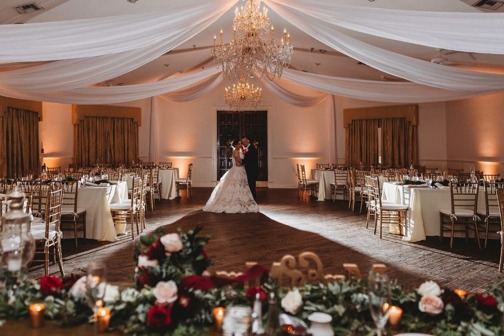 The-Highland-Manor-Couple standing in middle of reception ballroom with roses in foreground