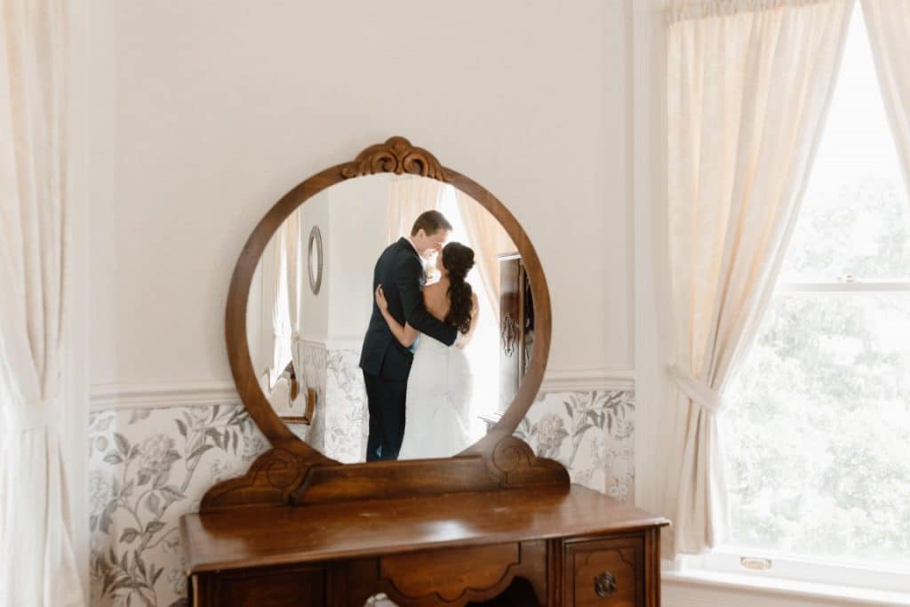The-Highland-Manor-Reflection of Bride and Groom in antique round mirror vanity