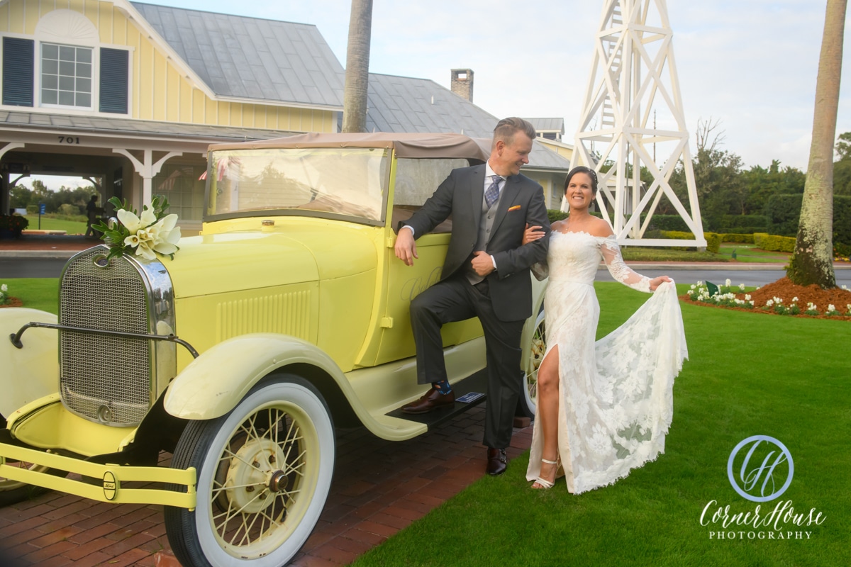 bride and groom in yellow classic car in front of golf course