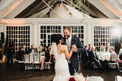 Bride and groom share their first dance in the elegant glass-ceilinged ballroom at Heathrow Country Club in Lake Mary Florida while wedding guests look on from candlelit reception tables