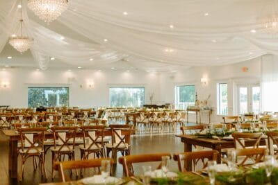 wedding reception, indoors, chandeliers, white sheet fabric on the ceiling, wood tables, set for dinner, wooden chairs, Orlando, FL