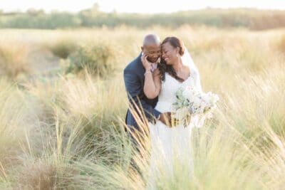 Bride and Groom standing in a field, grass blowing around them, Orlando, FL
