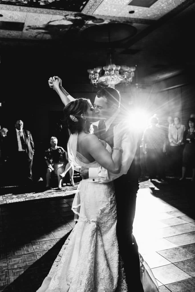 Our DJ Rocks - bride and groom kissing on dance floor with held hands raised in the air