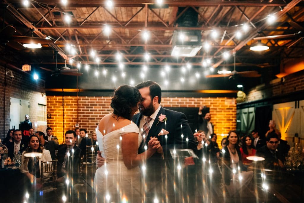 Our DJ Rocks - artsy shot of bride and groom dancing surrounded by market lighting
