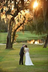 bride and groom kissing on tree-lined golf course, sunset, Orlando, FL