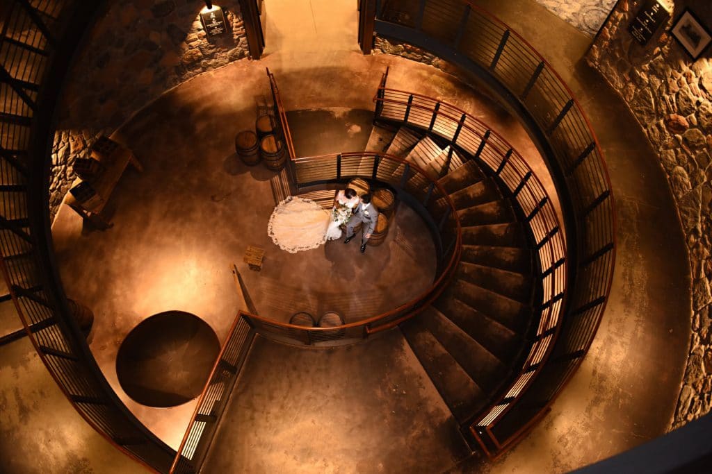 Rhodes Studios Photography and Video - aerial shot of bride and groom at bottom of spiral stairs