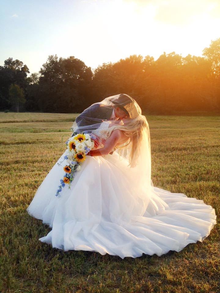 Rhodes Studios Photography and Video - country bride and groom kissing in field at sunset