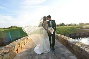 bride and groom kissing on stone bridge, water below, Orlando, FL