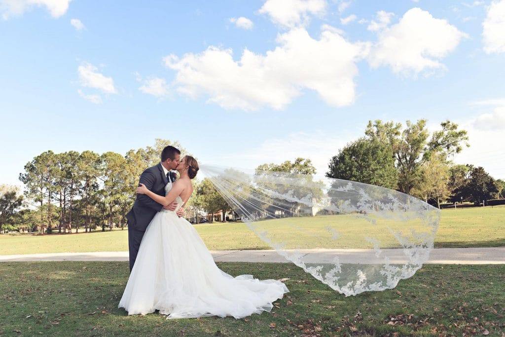 Rhodes Studios Photography and Video - bride and groom kissing while wind blows veil