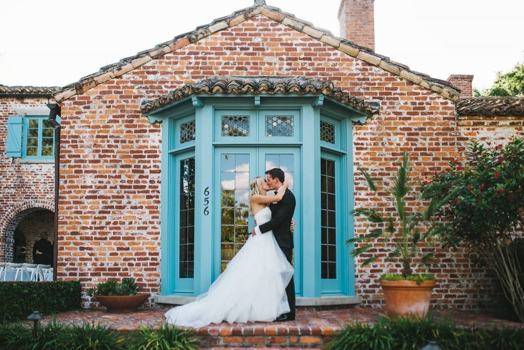 Rudy & Marta Photography - bride and groom kissing in front of bright blue door