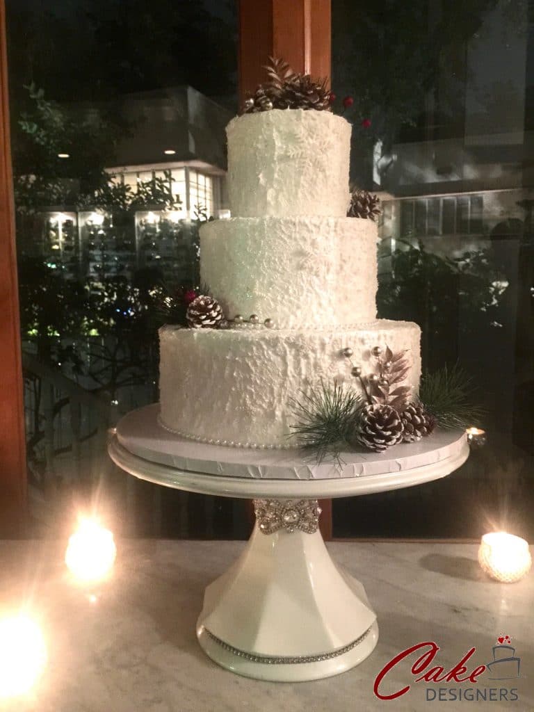 3 tier winter snow look cake with greens and pinecones