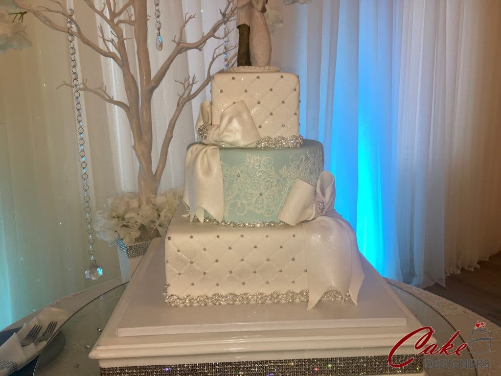 3 tier cake with blue center layer, embellishments and bows