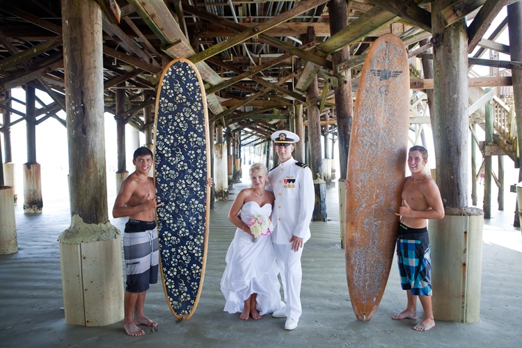 Lori Barbely - military couple posing with surfers under pier