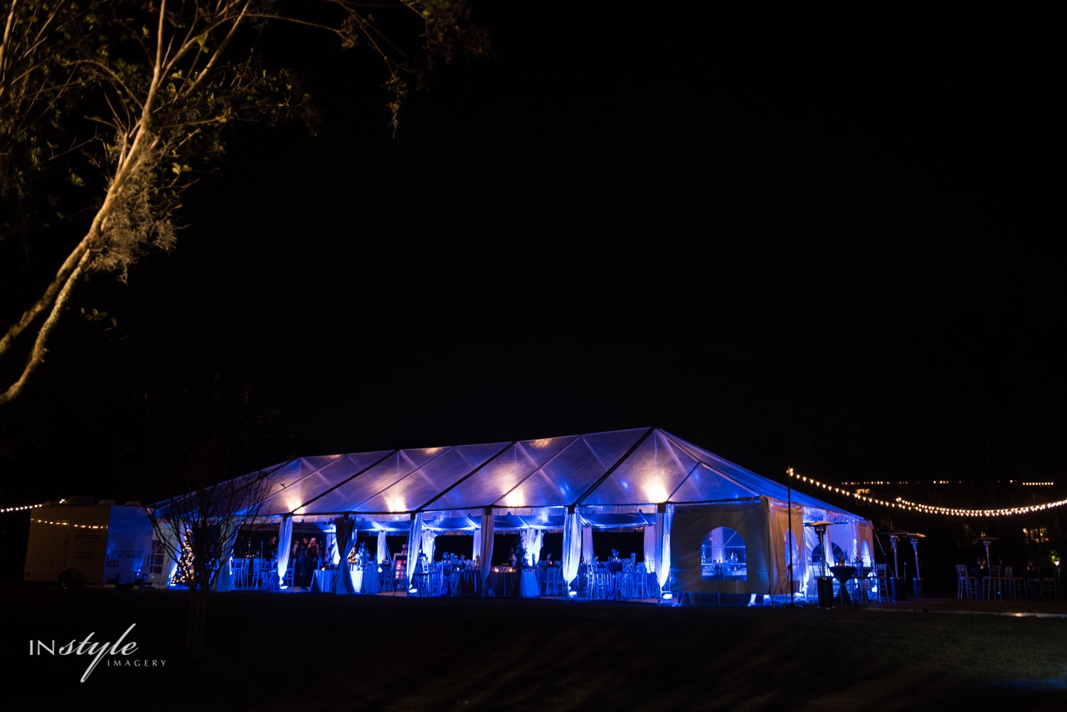 transparent wedding tent at night lit by blue uplighting
