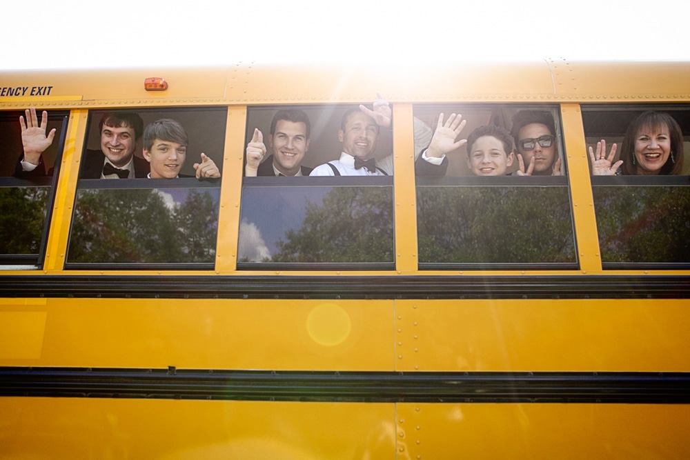 wedding party waving from school bus windows
