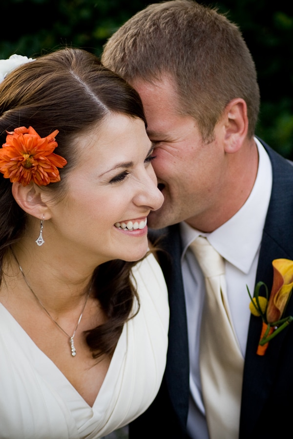 bride laughing while groom whispers in her ear