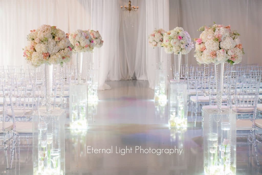 tall flower centerpieces in clear vases with clear Chiavari chairs by Atmospheres Floral