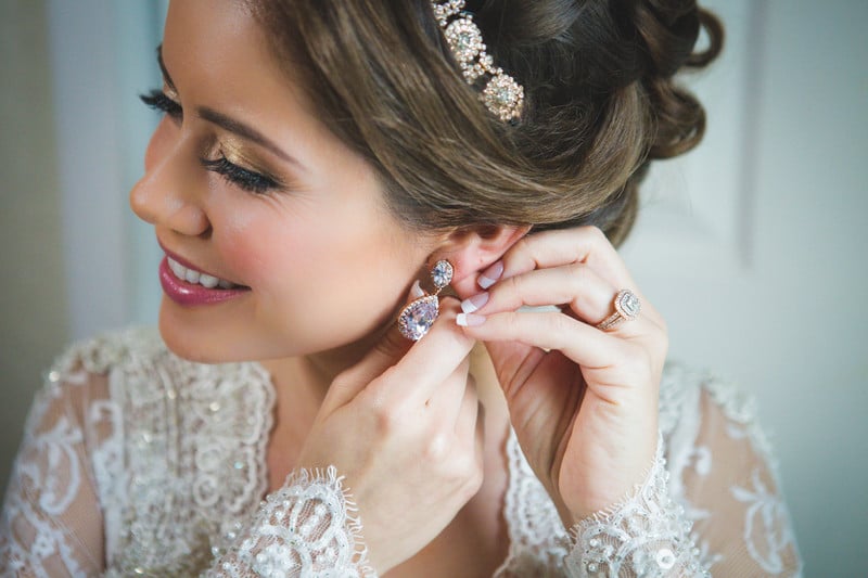 Laura Reynolds Artistry - bride putting on earrings