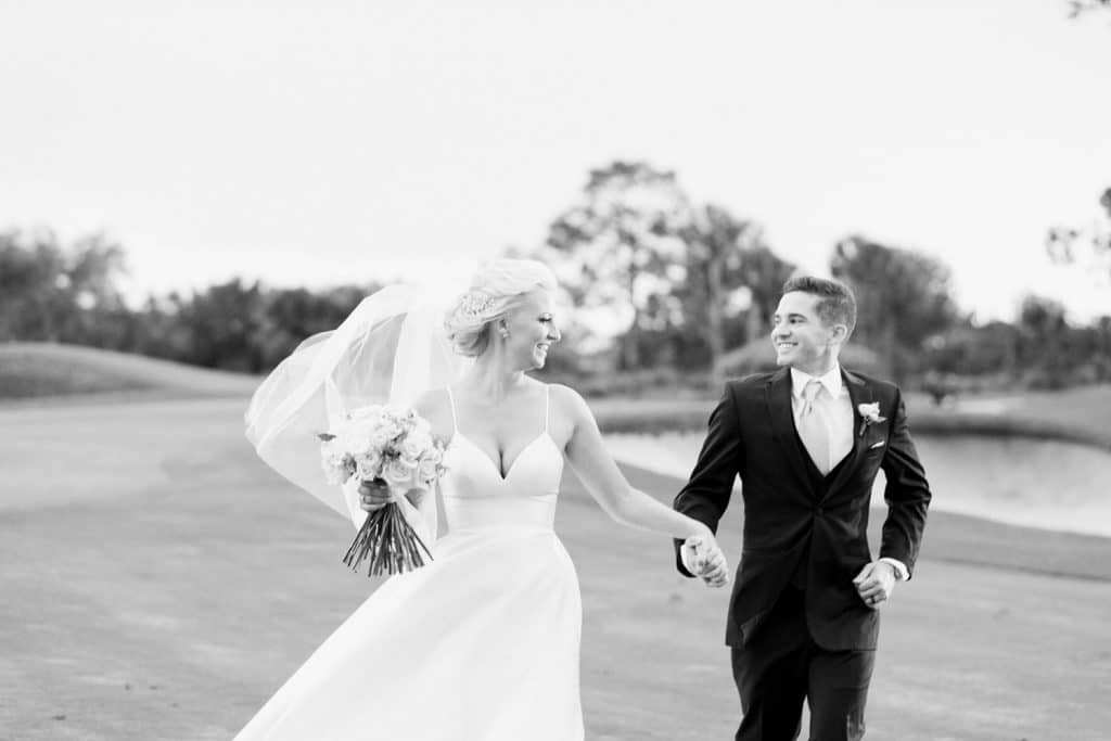 Bumby Photography black and white photograph of a bride and groom smiling and walking on a golf course