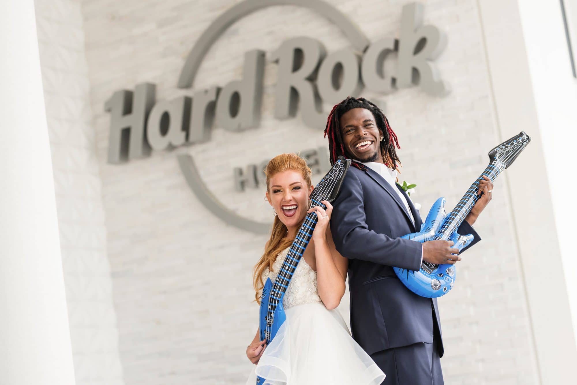 Hard Rock Hotel Daytona Beach - newlyweds playing pretend guitar in front of Hard Rock logo