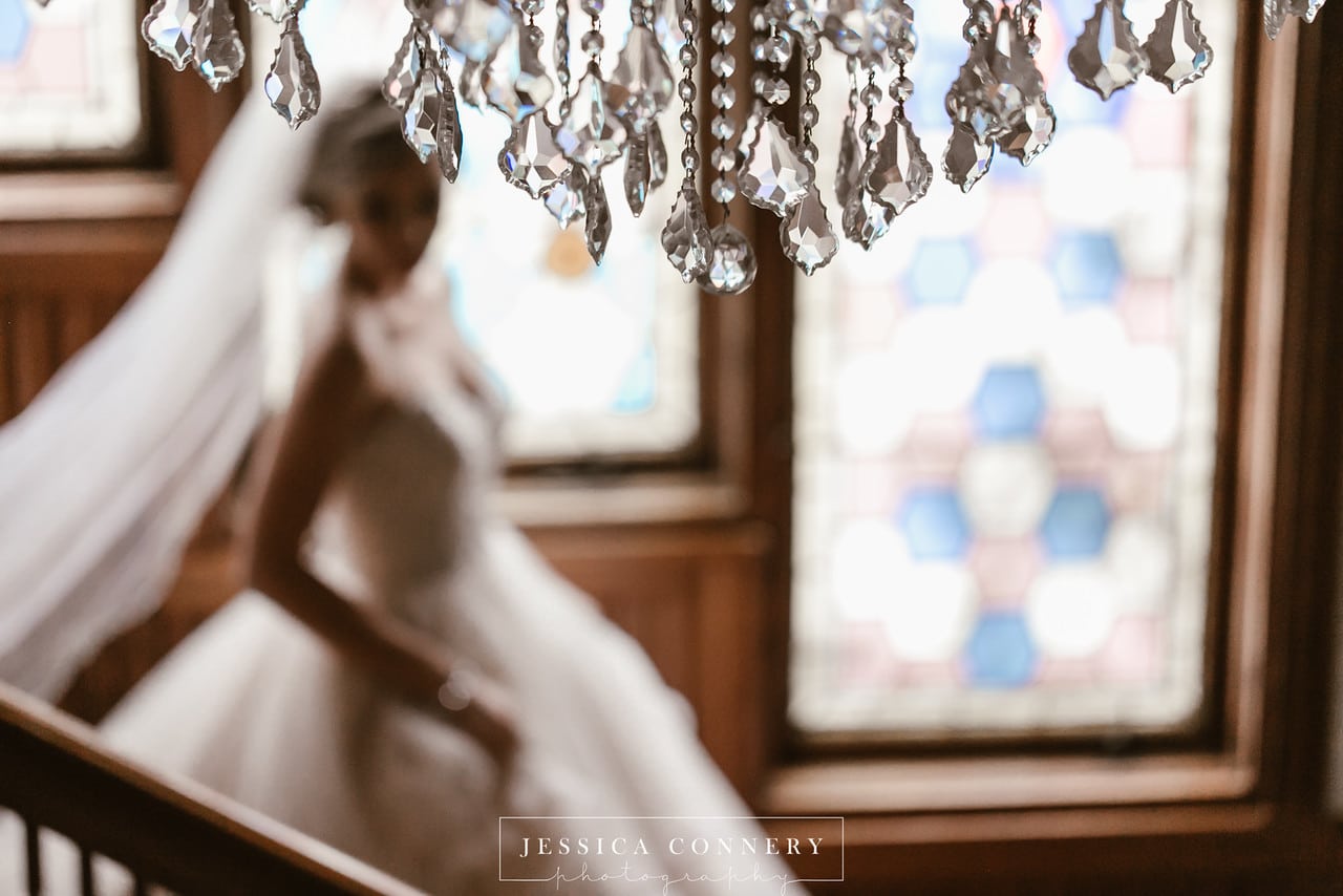 Stetson Mansion - detailed shot of crystal chandelier with bride in background on staircase