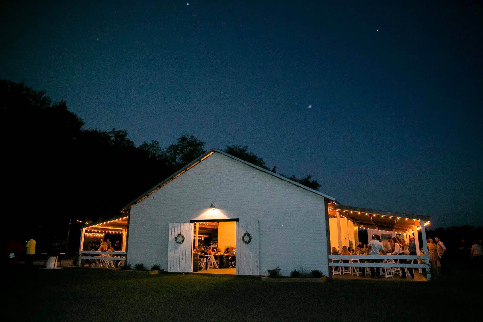 The Orange Blossom Barn - white barn lit up with market lighting