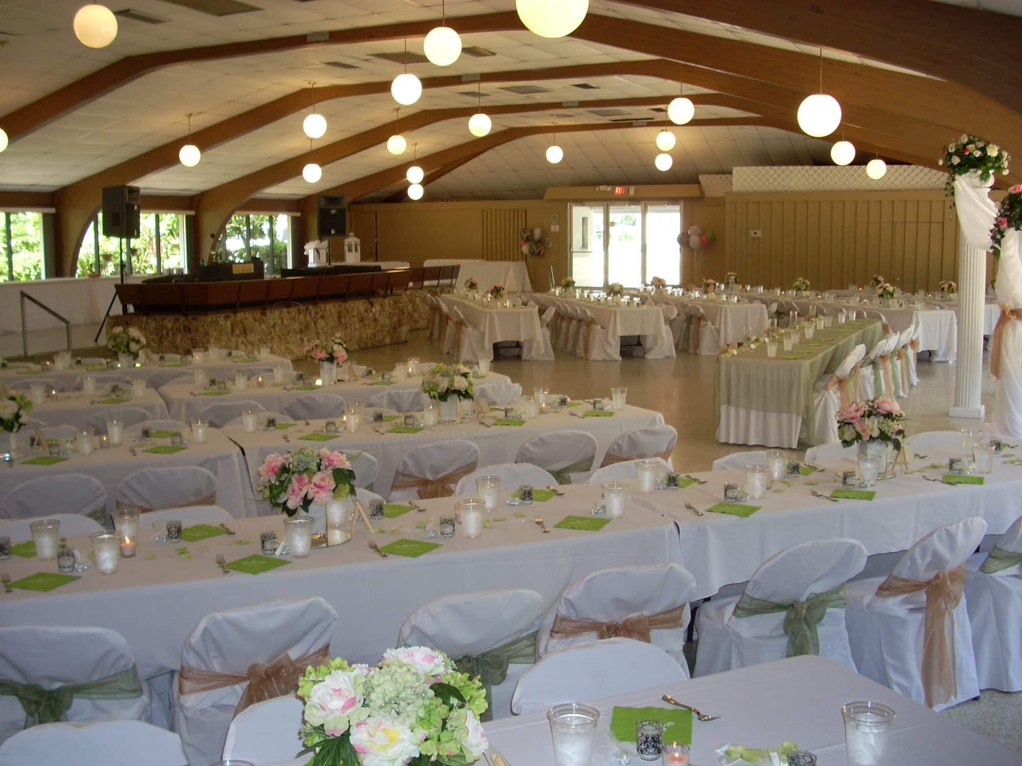 Venue on the Lake - long reception tables in hall with exposed, arched beams