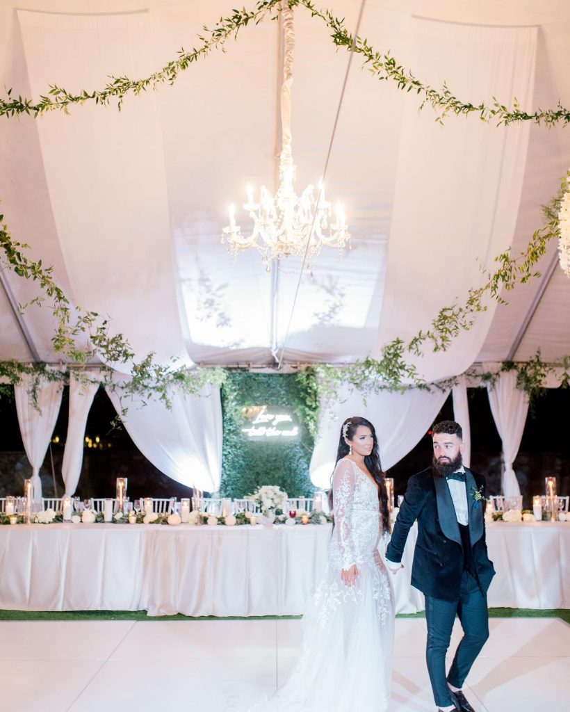 Orlando Wedding and Party Rentals, bride and groom in tent with greens and chandelier