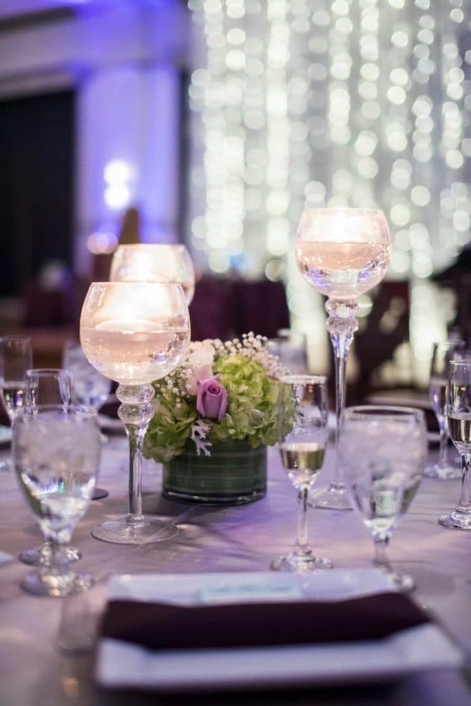 table setting of silver and grey with candles and floral centerpieces