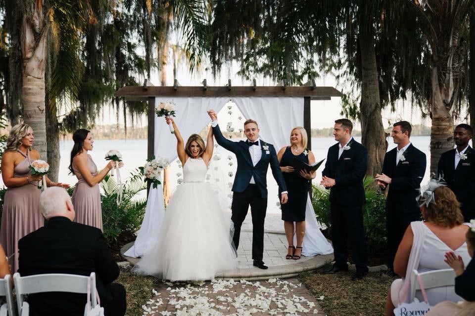 bride and groom standing on altar at outdoor wedding on a lake with Hearts & Souls Officiant an Orlando Wedding Officiant looking on