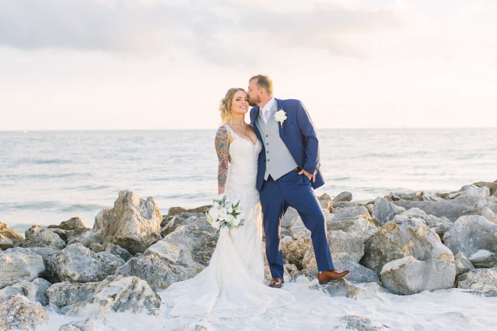couple standing against rocks at the beach just married by Hearts & Souls Officiant an Orlando Wedding Officiant