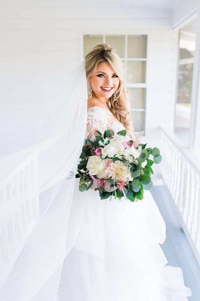 bride on white patio with hair and make-up by by kristy's artistry design team