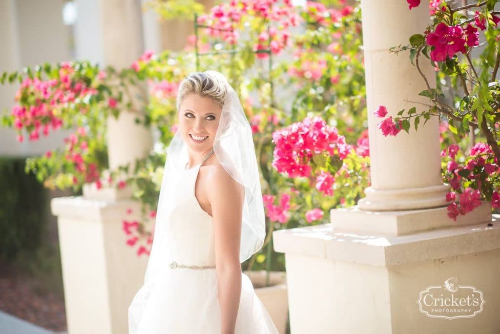 glowing bride with pink flowers standing outside with hair and make-up by kristy's artistry design team