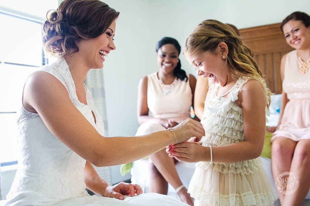 Sugar Pop Productions - Flower girl putting bracelet on laughing bride
