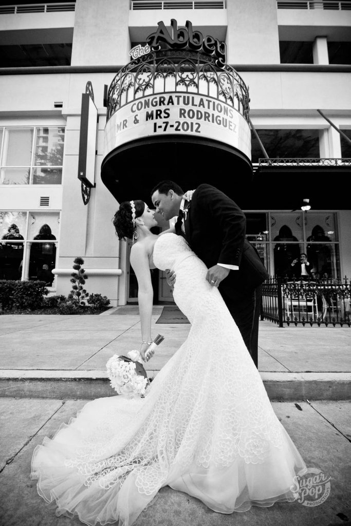 Sugar Pop Productions - bride and groom kissing in front of venue with personalized marquee