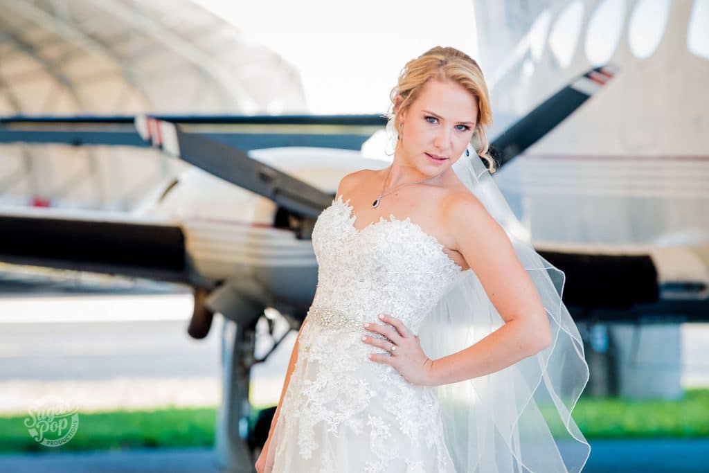 Sugar Pop Productions - bride posing in front of small plane